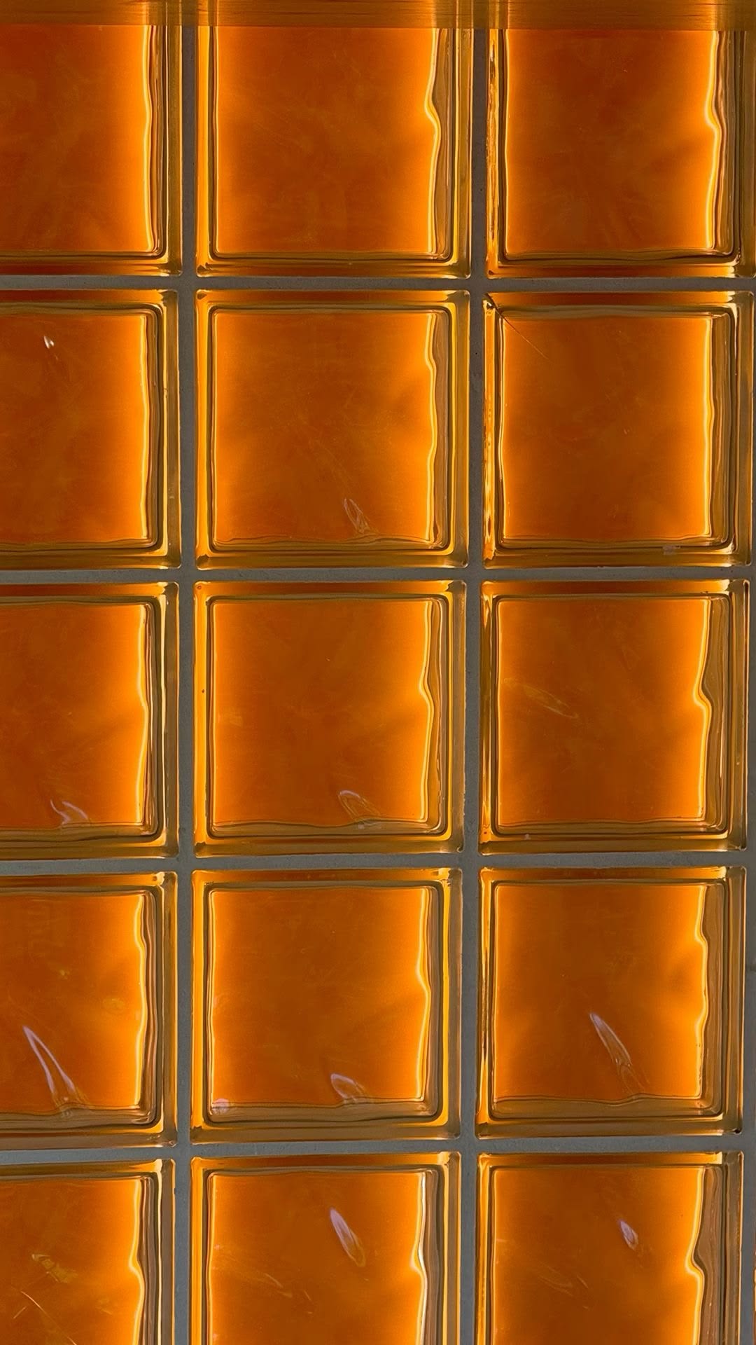 Wall of amber glass blocks glowing with warm sunset light