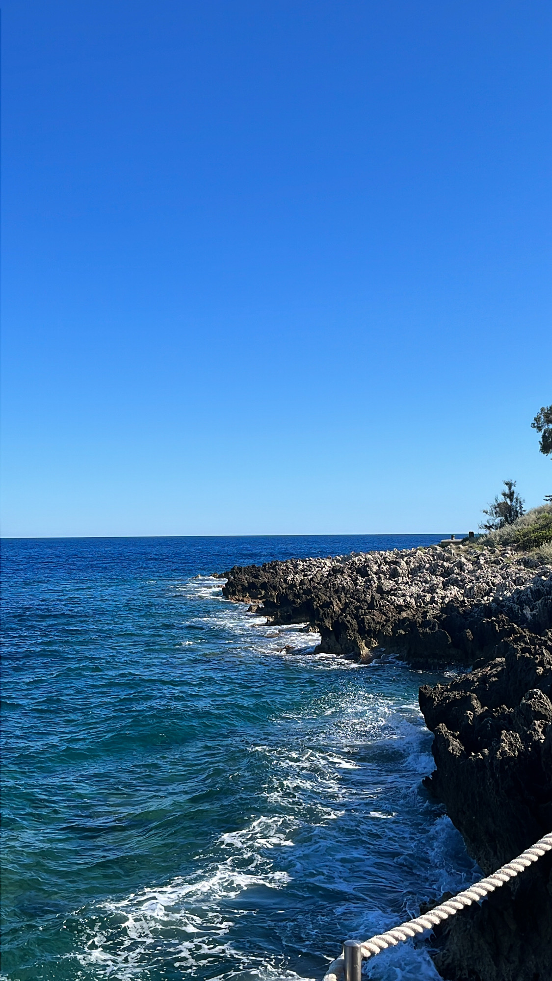 Rocky coastline of Cap d'Antibes with deep blue Mediterranean and white surf