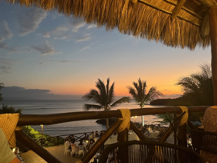 Sunset over the sea under a thatched roof