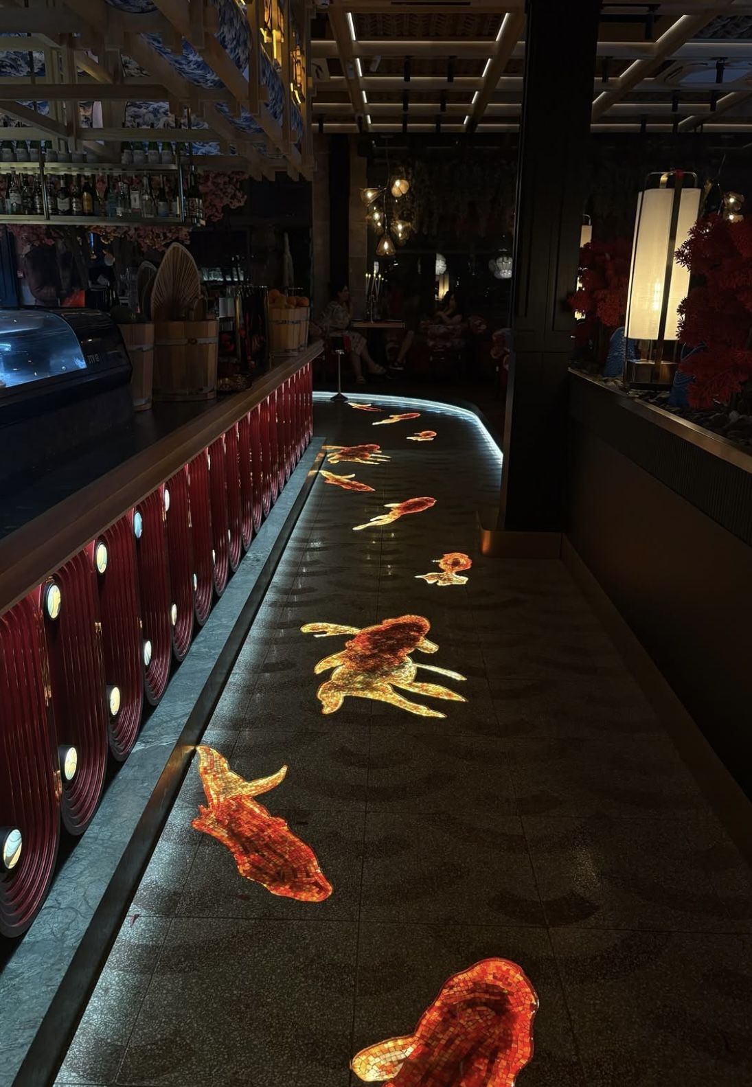 Illuminated koi fish mosaic swimming across a dark restaurant floor