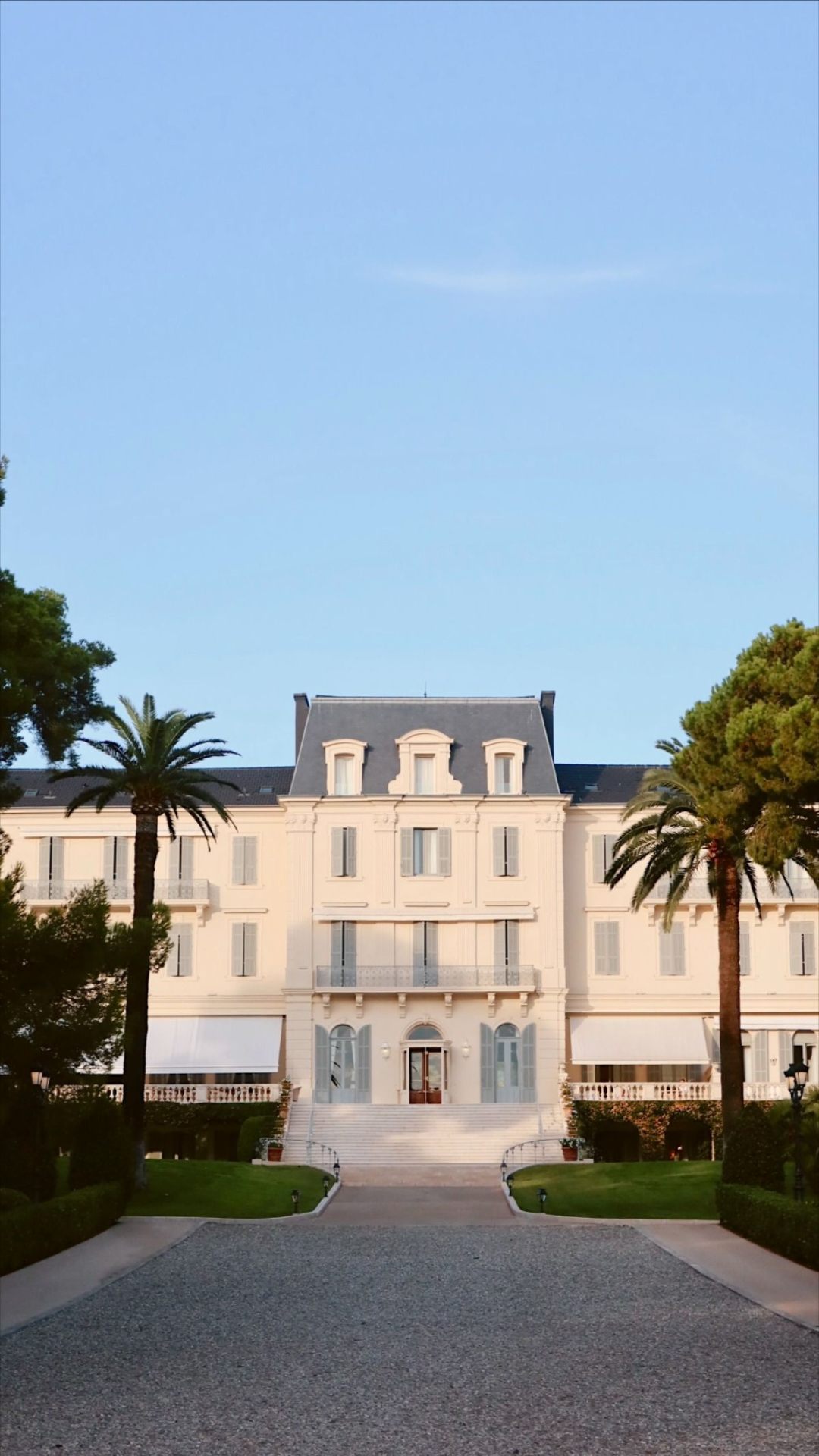 Hotel du Cap-Eden-Roc — cream Belle Époque façade framed by palm trees and umbrella pines