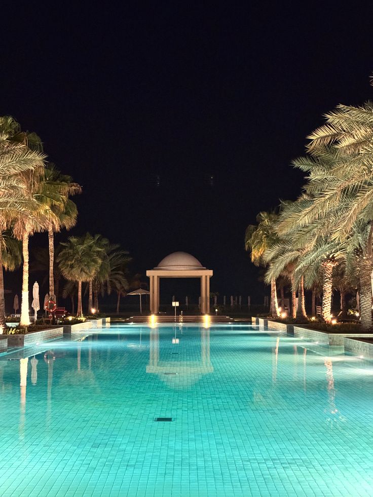 Palm-lined resort pool lit at night with a domed pavilion at the far end, Rixos Al Mairid Ras Al Khaimah