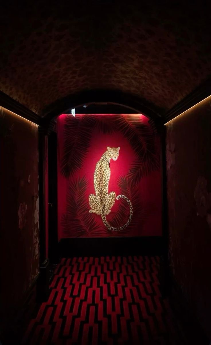 Dark corridor with leopard ceiling leading to a red leopard mural