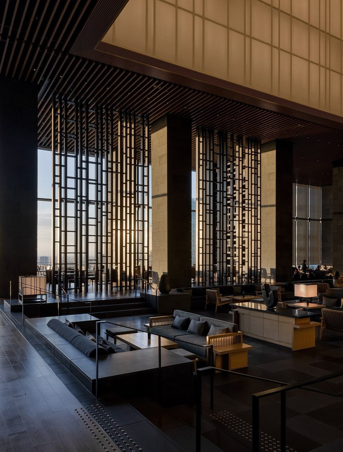 Aman Tokyo lobby lounge with washi paper ceiling, tall wooden lattice screens and golden sunset light