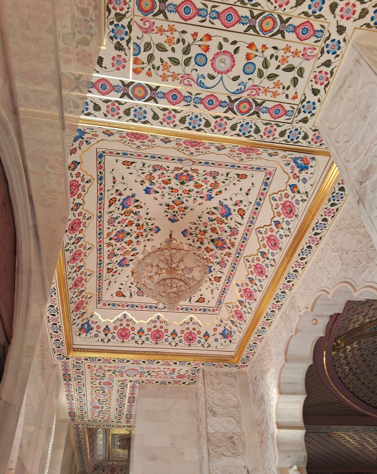 Ornate ceiling painted with pink and blue flowers and a crystal chandelier