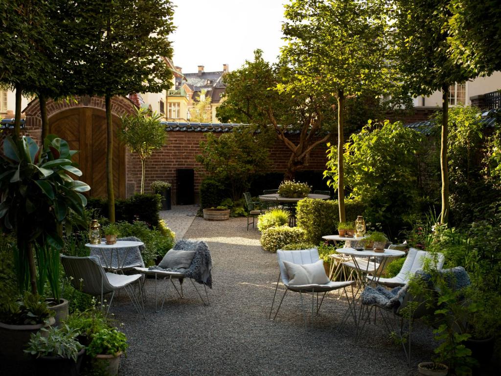 Ett Hem — the walled garden courtyard with pleached trees, gravel paths and lantern-lit seating in Stockholm