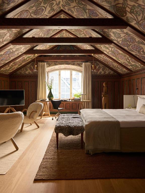 Ett Hem — attic bedroom with hand-painted timber ceiling, sheepskin bench and sculptural lounge chairs