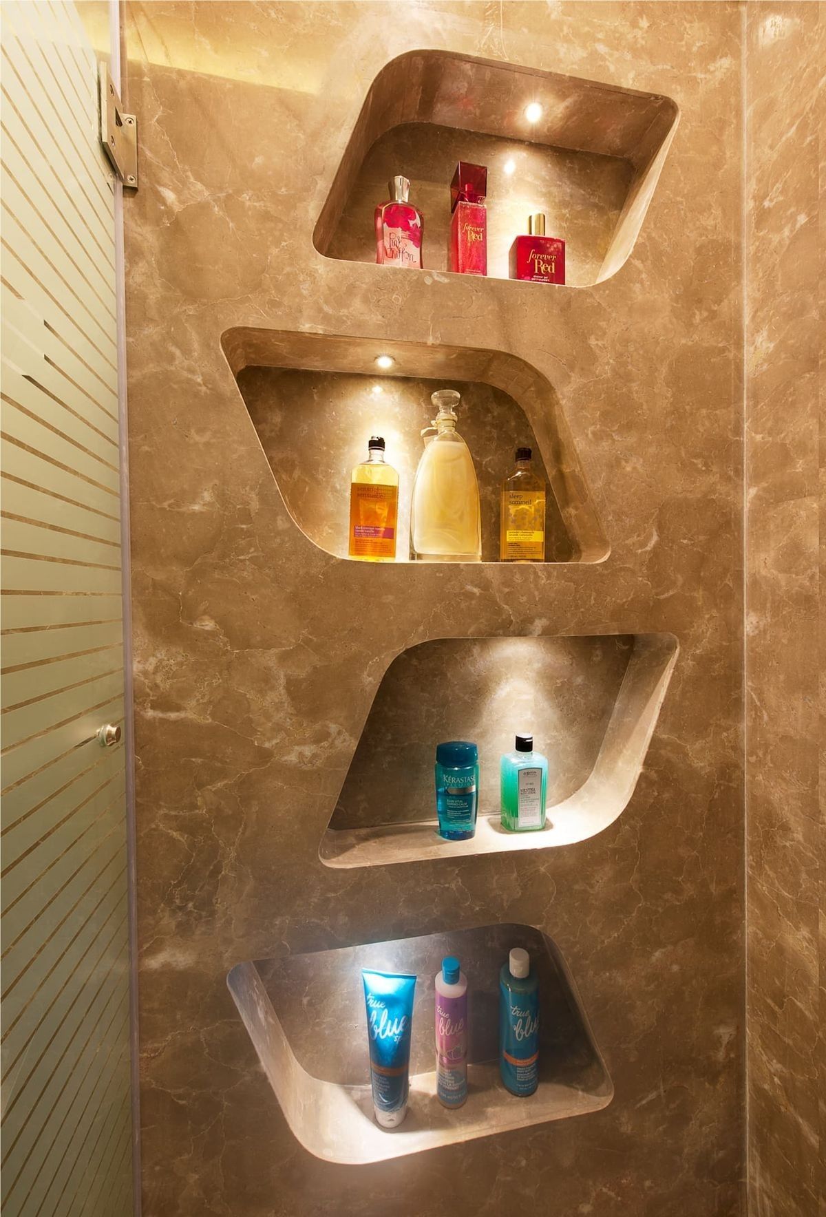 Sculpted marble shower niches with spotlights holding bottles