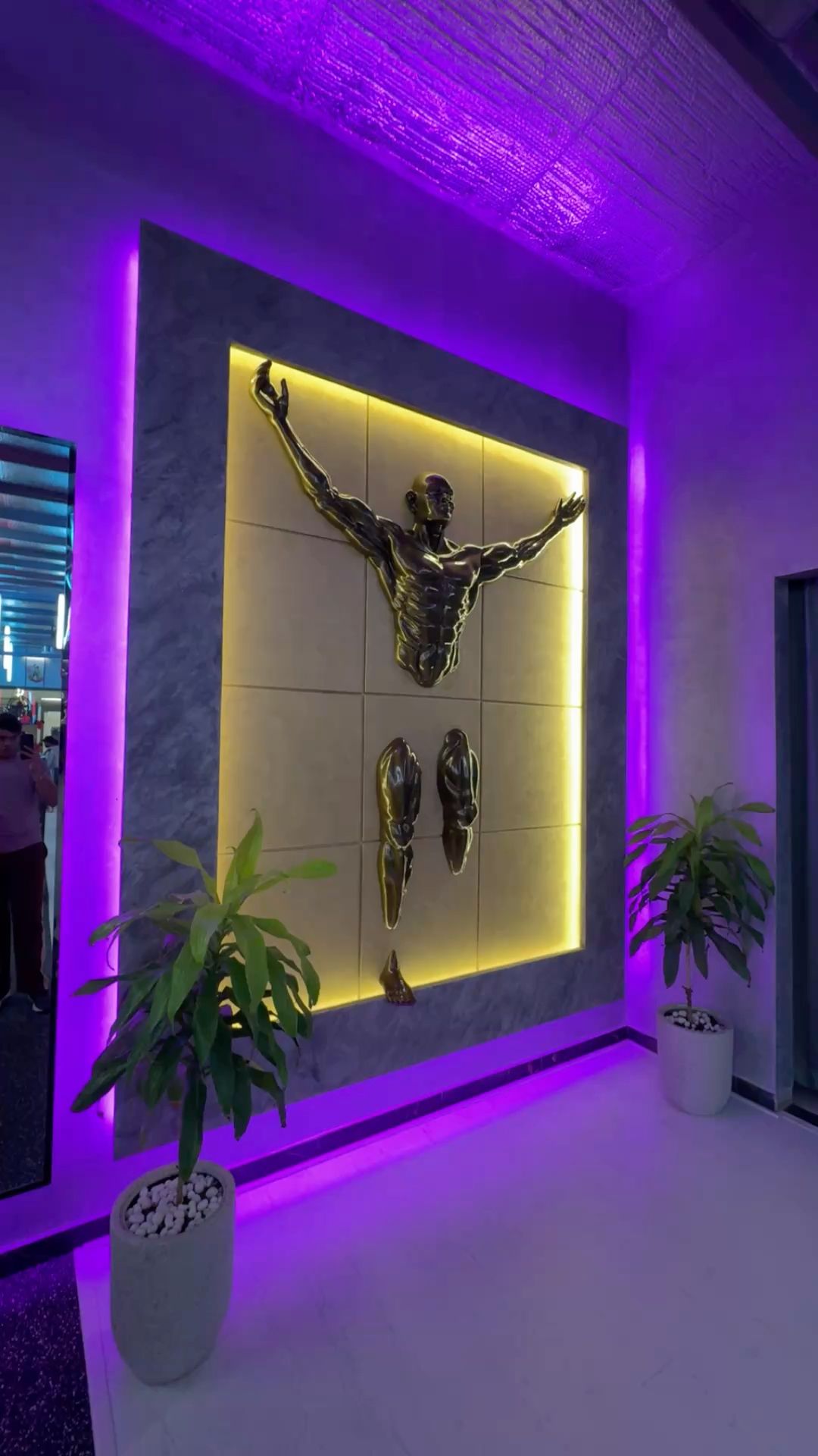 Bronze figure bursting from a backlit gold niche in a purple-lit lobby