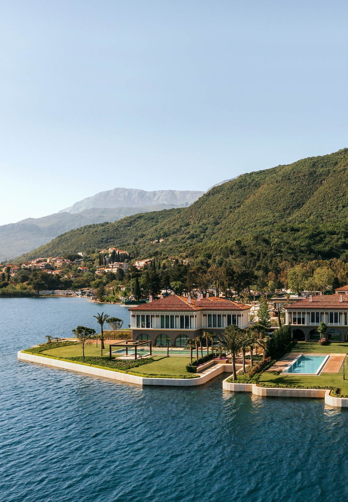 One&Only Portonovi — aerial view of terracotta-roofed villas on the Boka Bay waterfront beneath Montenegrin mountains