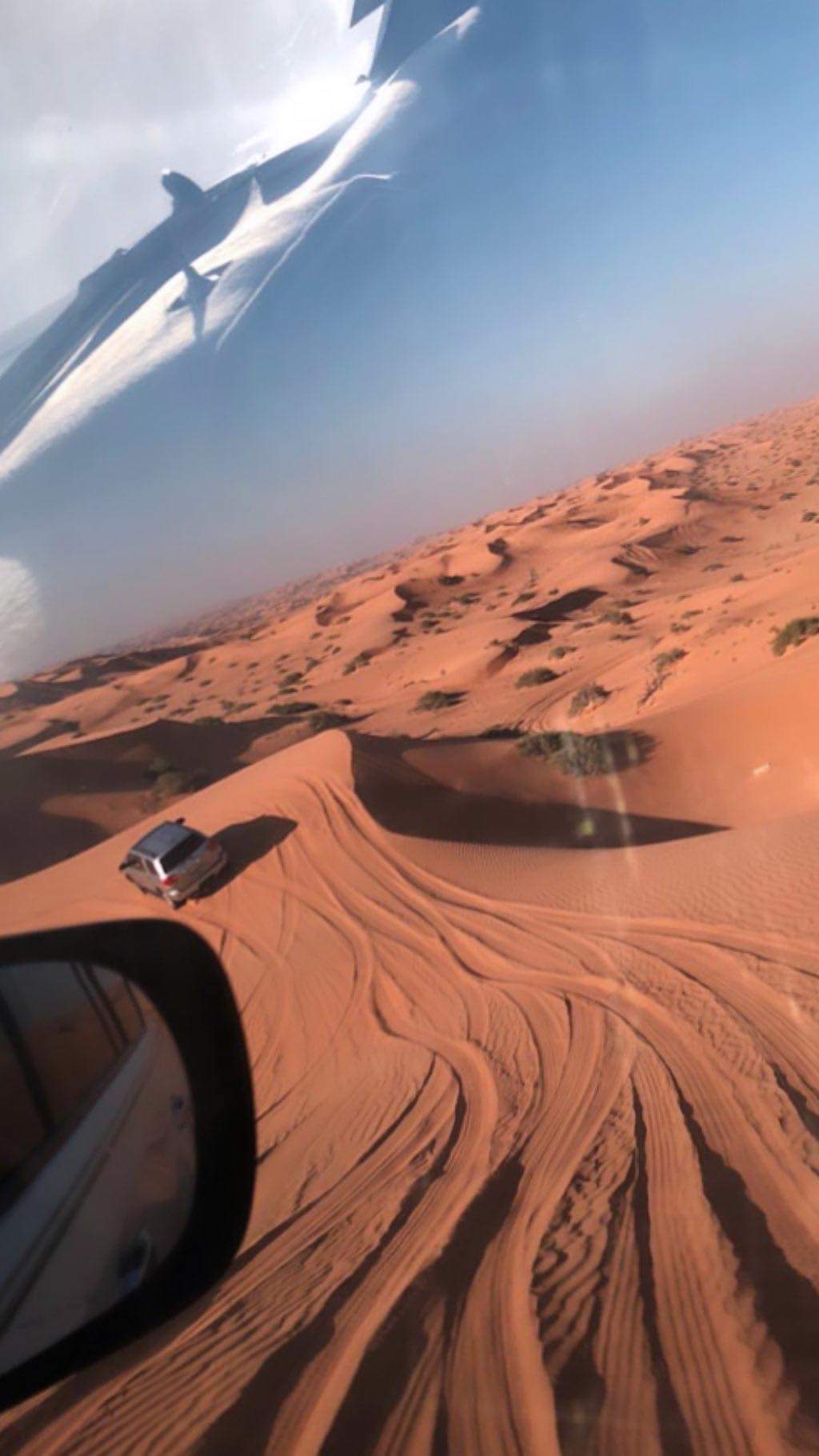 Land Cruiser cresting a red dune during a desert drive