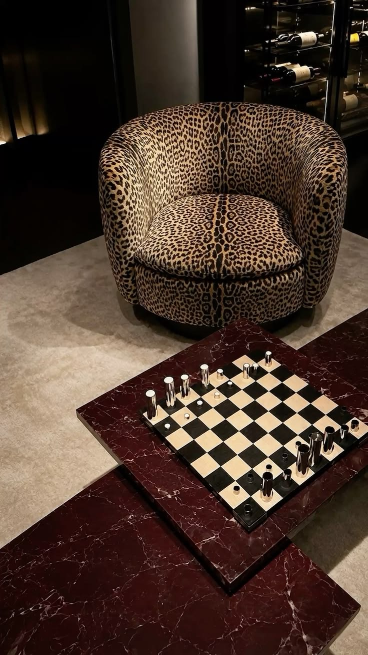 Leopard-print tub chair beside a marble chess table in a dark wine room
